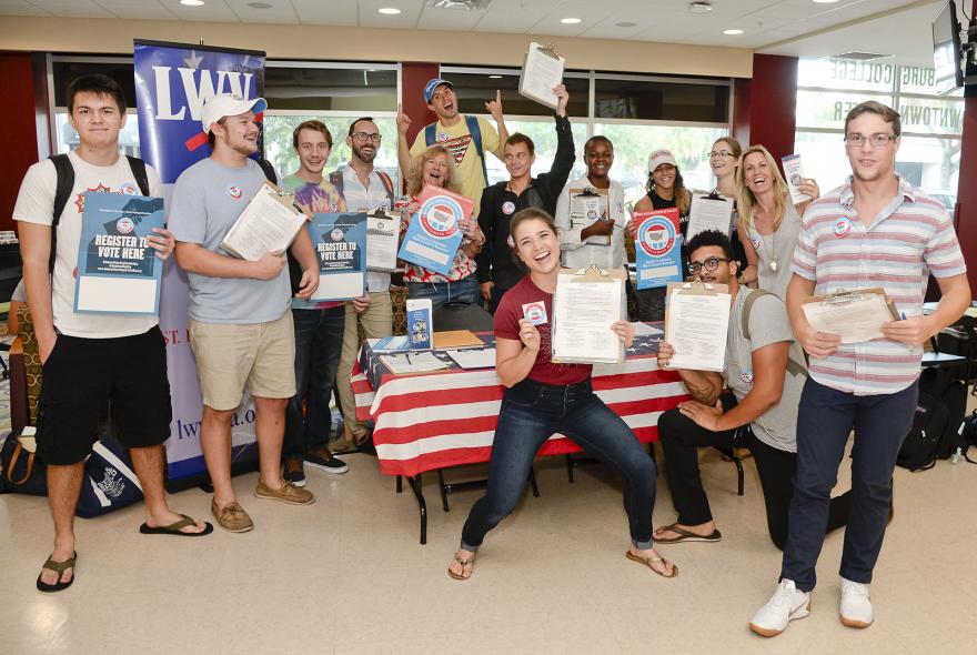 Group of people holding voter registration materials at a booth