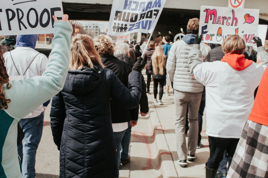 People marching holding picket signs for gun safety