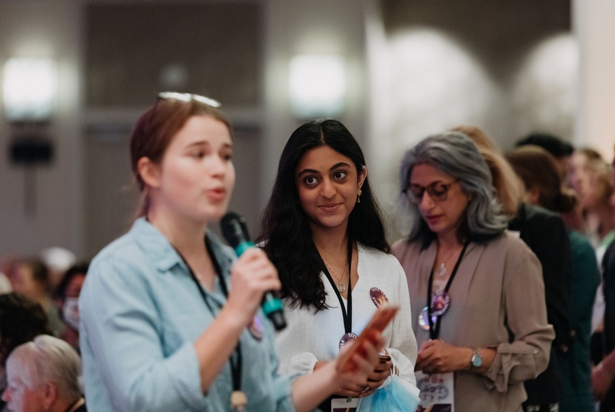 Woman at microphone asking a question, with a queue of women at LWV Convention